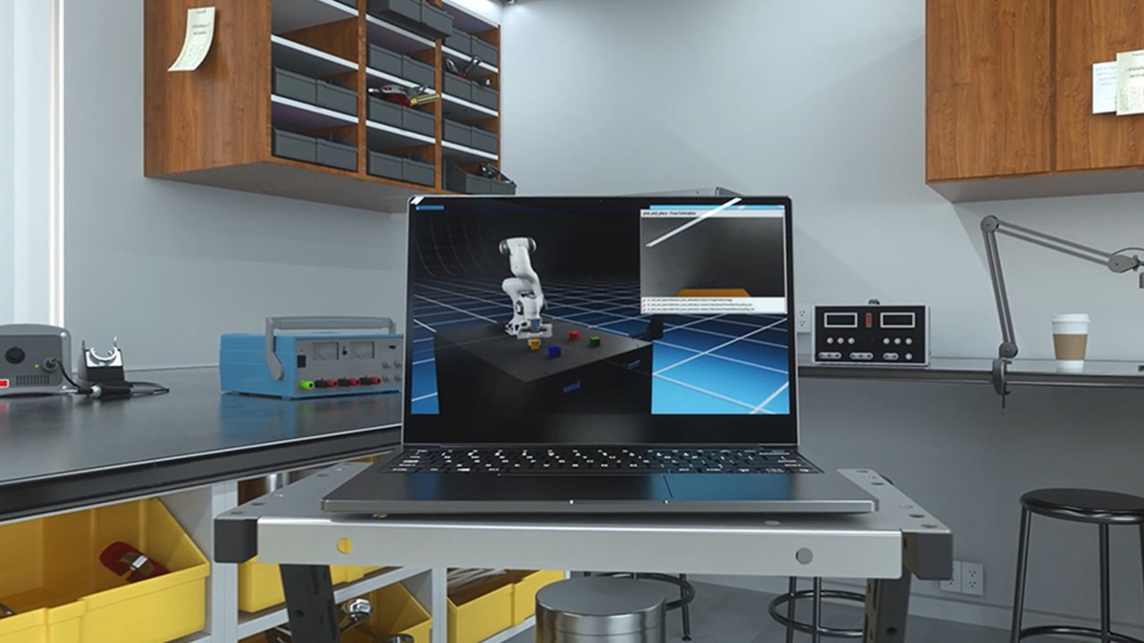 在车间桌子上显示 3D 机械臂设计的笔记本电脑